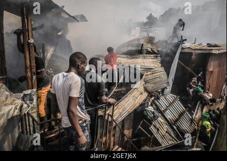 Nairobi, Kenya. 17 août 2021. Les résidents grimpent sur les toits pour aider à faire feu à Bombolulu Kibera, Nairobi. La plupart des résidents se sont réunis pour aider à mettre fin à un incendie qui s'est produit mardi après-midi à partir des fils électriques enchevêtrés qui alimentent différentes maisons. Le feu a rasé douze maisons et propriétés laissant la plupart des résidents sans nulle part pour se tourner vers la plupart des résidents sans emploi. (Credit image: © Donwilson Odhiambo/ZUMA Press Wire) Banque D'Images