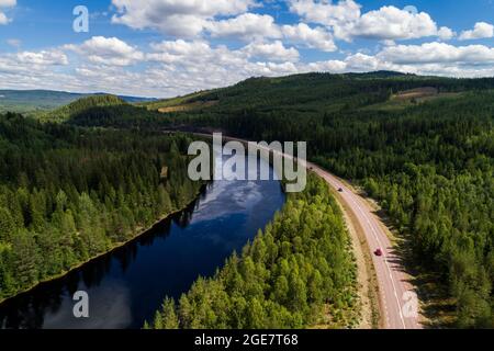 Vue aérienne à grand angle de la rivière et de la route traversant la forêt et le paysage montagneux dans le nord de la Suède Banque D'Images