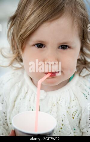 Une petite fille mignonne boit du lait avec de la paille Banque D'Images