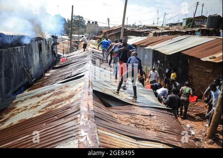 Nairobi, Kenya. 17 août 2021. Les habitants de la région travaillent ensemble pour déclencher un incendie qui a rasé douze maisons à Bombolulu, Kibera.les résidents se sont joints aux mains pour aider à déclencher un incendie qui s'est produit aujourd'hui après-midi à partir de fils électriques enchevêtrés alimentant différentes maisons en électricité. Le feu a rasé douze maisons et propriétés laissant la plupart des résidents bloqués. Crédit : SOPA Images Limited/Alamy Live News Banque D'Images