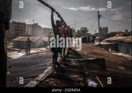 Nairobi, Kenya. 17 août 2021. Les résidents sont vus sur le toit en train d'essayer de déclencher un incendie à Bombolulu Kibera.les résidents se sont joints aux mains pour aider à faire un incendie qui s'est produit aujourd'hui après-midi à partir de fils électriques enchevêtrés alimentant différentes maisons en électricité. Le feu a rasé douze maisons et propriétés laissant la plupart des résidents bloqués. (Photo de Donwilson Odhiambo/SOPA Images/Sipa USA) crédit: SIPA USA/Alay Live News Banque D'Images