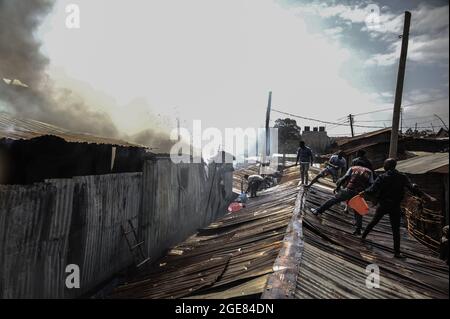 Nairobi, Kenya. 17 août 2021. Les habitants vus sur le toit en train d'essayer de faire feu à Bombolulu, Kibera.les résidents se sont joints aux mains pour aider à faire feu qui s'est produit aujourd'hui après-midi à partir de fils électriques emmêlés alimentant différentes maisons. Le feu a rasé douze maisons et propriétés laissant la plupart des résidents bloqués. (Photo de Donwilson Odhiambo/SOPA Images/Sipa USA) crédit: SIPA USA/Alay Live News Banque D'Images