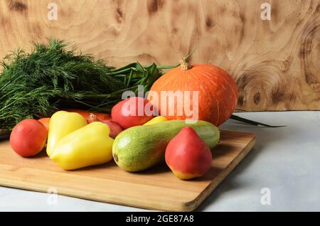 Un ensemble de légumes sur une planche à découper en bois. Citrouille, tomates, oignons, courgettes, poivron, carottes et aneth sur fond de bois. Sélectif FO Banque D'Images