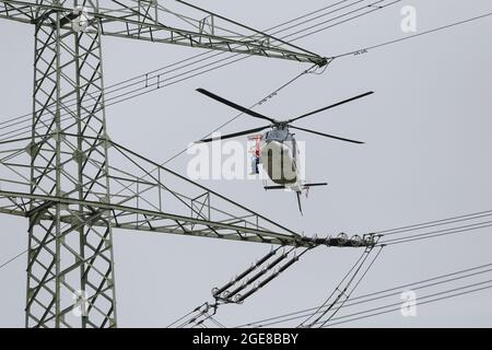 Placer des marqueurs de protection des oiseaux sur une ligne électrique avec l'aide d'un hélicoptère et d'un monteur assis à l'extérieur de l'Allemagne, Affoldern, 2017-04-10. Banque D'Images