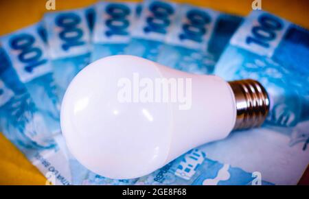 Brésil. 17 août 2021. Dans cette photo illustration une lampe à diodes électroluminescentes (LED) vu sur plusieurs billets d'argent réel brésiliens. Concept de prix de l'électricité. Facture d'électricité. Crédit : SOPA Images Limited/Alamy Live News Banque D'Images