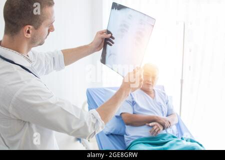 Le médecin vérifie et regarde le film radiographique et explique la maladie au vieux patient Banque D'Images