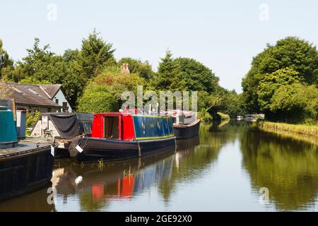 Des bateaux étroits amarrés sur le canal de Leeds et Liverpool en direction de Burscough avec un pont tournant au loin Banque D'Images