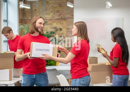 Jeunes travaillant comme bénévoles et emballant les boîtes Banque D'Images