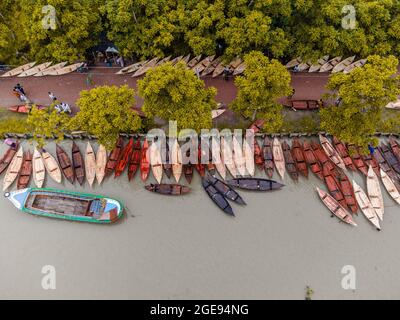 Barishal, Barishal, Bangladesh. 18 août 2021. Les constructeurs de bateaux de l'hebdomadaire 'Noukar Haat' (marché de bateaux) à Kuriana, sous la direction de Swarupkathi upazila du district de Pirojpur dans la division Barishal au Bangladesh, font des affaires de vive pendant cette saison de la Monsoon. Le marché de deux kilomètres de long est réputé pour le commerce de différentes variétés de bateaux pendant la saison de la mousson. Le marché se déroule tous les vendredis de mai à novembre. 'Panis'' ou 'Pinis'', 'ingi' et 'Naak Golui'' sont les types de bateaux disponibles à la vente, construits par des artisans locaux des Muktahar, Chami, Boldia, Inderhaat, B. Banque D'Images