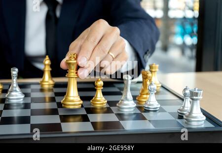 Un homme d'affaires en costume tient une figure de roi d'échecs sur le concept de conseil d'administration du concept de stratégie d'échecs Banque D'Images