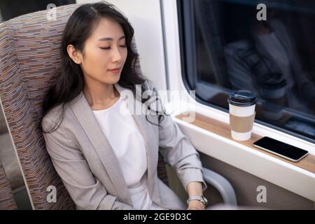 Jeune femme d'affaires chinoise reposant sur un train à grande vitesse Banque D'Images