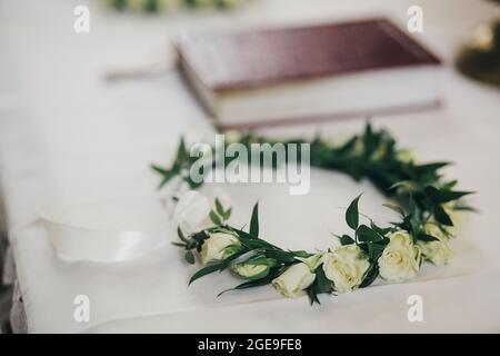 Belle couronne florale moderne avec roses sur nappe blanche sur autel dans l'église pour le mariage Saint. Cérémonie de mariage dans la cathédrale. Corbeau fleuri moderne Banque D'Images