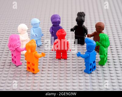 Tambov, Fédération de Russie -12 août 2021 figurines LEGO monochromes colorées entourant une figurine rouge et le pointant vers lui. Banque D'Images