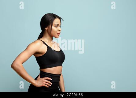 Entraîneur personnel. Femme sportive noire confiante posant sur fond bleu studio et regardant l'espace libre Banque D'Images