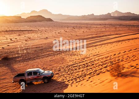 Un touriste Mitsubishi jeep au coucher du soleil dans le désert jordanien à Wadi Rum ou la vallée de la Lune. Banque D'Images