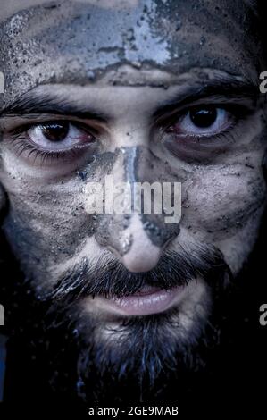 portrait d'un homme du moyen-orient barbu avec le visage couvert de boue et un regard intense Banque D'Images