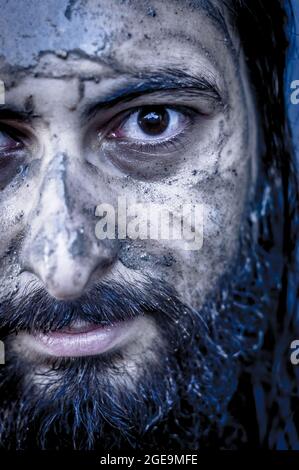 portrait d'un homme du moyen-orient barbu avec le visage couvert de boue et un regard intense Banque D'Images