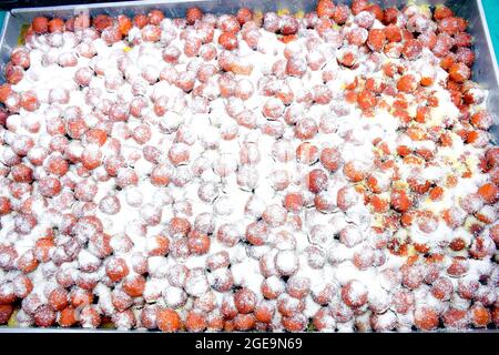 Beaucoup de jamuns gulab dans une grande assiette, orné de limaille de noix de coco séchées. Banque D'Images