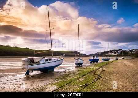 Lumière du soir sur divers voiliers amarrés sur la plage de la rivière Gannel à marée basse à Newquay, en Cornouailles. Banque D'Images