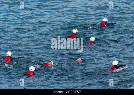 Vacanciers nageant dans la mer lors d'une aventure de copilotage à Newquay, en Cornouailles. Banque D'Images