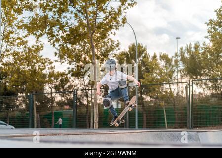 Un jeune garçon sautant avec un skateboard et montrant le cascades sur la rampe du skate Park Banque D'Images