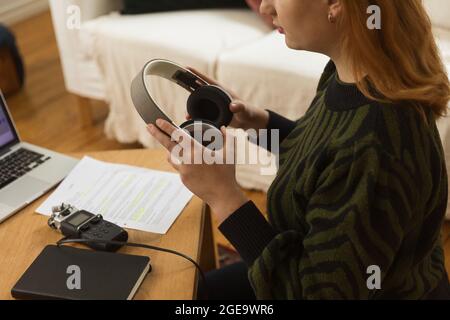 Vue latérale d'une femme méconnaissable avec casque se préparant à enregistrer un podcast à la table à la maison Banque D'Images