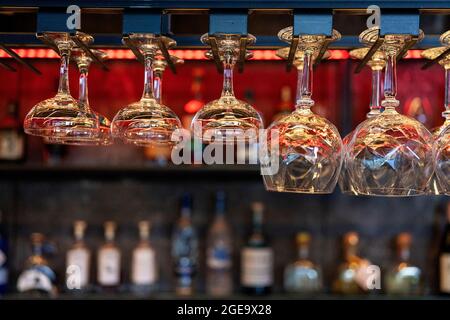 Plusieurs verres en cristal propres de forme et de taille différentes suspendus sur les étagères au-dessus du comptoir dans le bar Banque D'Images