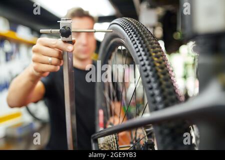 Roue de bicyclette de centrage principale mâle floue placée sur un support de truing dans un atelier de réparation moderne Banque D'Images