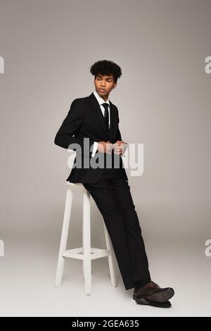 afro-américain dans la suite blazer de fesse tout en étant assis sur fond gris Banque D'Images