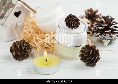 Produits de beauté et cônes de pin avec décoration naturelle et composition de bougies à éclairage vert sur une table en bois blanc Banque D'Images