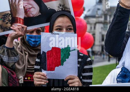 WESTMINSTER LONDRES 18 août 2021. Une jeune femme de la communauté afghane britannique tire le drapeau national de l'Afghanistan sur la place du Parlement en réaction à la prise de pouvoir par les talibans en Afghanistan. Le Premier ministre Boris Johnson a rappelé le Parlement alors que les MPS reviennent de leurs vacances d'été pour débattre de la crise en Afghanistan et amener 20,000 réfugiés afghans vulnérables . Credit amer ghazzal/Alamy Live News Banque D'Images