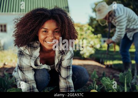 Belle paysanne souriante travaillant dans le potager organisant les produits se sentant active Banque D'Images