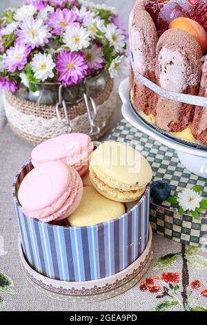 Macarons français, fleurs et gâteau éponge. Décoration de table de fête. Banque D'Images