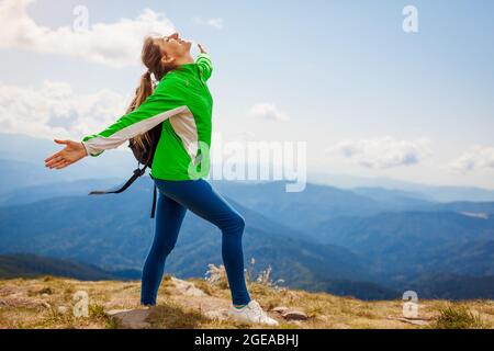 Excursion dans les montagnes carpathes. Une femme heureuse randonneur touristique avec sac à dos levant les bras au-dessus de Hoverla appréciant le paysage et l'air frais. Voyager en su Banque D'Images