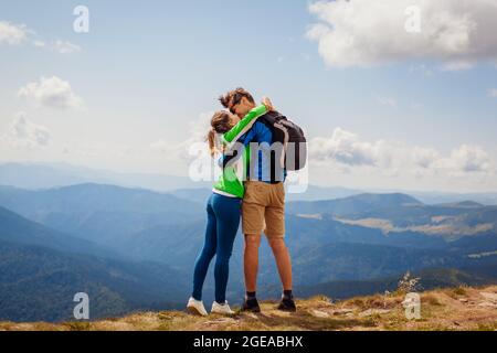 Couple heureux de randonneurs en lune de miel embrassant au sommet de la montagne Hoverla. Les touristes heureux Voyage à Carpates. Tourisme en Ukraine d'été Banque D'Images