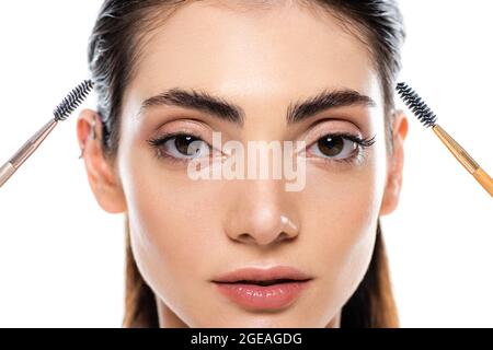 jeune femme portant des brosses pour sourcils isolées sur blanc Banque D'Images