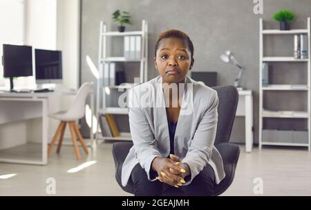 Une femme d'affaires déçue et sans impression, assise sur une chaise de bureau et regardant la caméra Banque D'Images