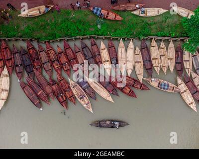 Vue aérienne des constructeurs de bateaux fabriquent des bateaux en bois à "Noukar Haat" (marché de bateaux) à Kuriana sous le Swarupkathi upazila du district de Pirojpur. Le marché de Noukar Haat, d'une longueur de deux kilomètres, est réputé pour le commerce de différentes variétés de bateaux pendant la saison de la mousson. Le marché se déroule tous les vendredis de mai à novembre. “Panis” ou “Pinis”, “Dingi” et “Naak Golui” sont les types de bateaux disponibles à la vente, construits par des artisans locaux des Muktahar, Chami, Boldia, Inderhaat, Boitha Kata, Villages de Dubi et Kathali. Le 18 août 2021 à Barishal, au Bangladesh. Photo de M Banque D'Images