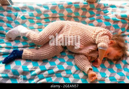 Enfant avec bandage sur la fracture du talon de la jambe. Pied droit cassé, os, mollet, cheville, jambe en plâtre, une petite tache. Petit garçon dormant sur un blanke bleu Banque D'Images