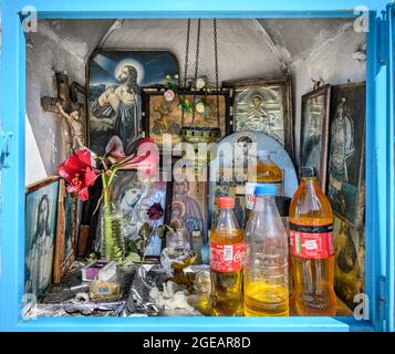 L'intérieur d'un sanctuaire grec orthodoxe en bord de route présentant des icônes religieuses, des bouteilles d'huile sainte et des brûleurs à encens. Arcadia, Péloponnèse, Grèce Banque D'Images