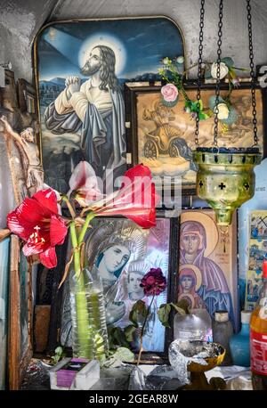 L'intérieur d'un sanctuaire grec orthodoxe en bord de route présentant des icônes religieuses, des bouteilles d'huile sainte et des brûleurs à encens. Arcadia, Péloponnèse, Grèce Banque D'Images