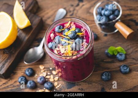 Smoothie aux myrtilles dans un pot en verre sur fond de table en bois. Repas végétalien sain Banque D'Images