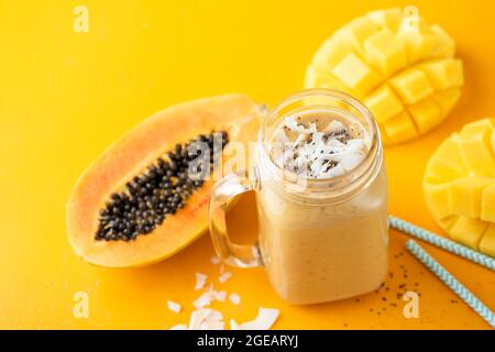 Smoothie à la papaye de mangue tropicale dans un pot en verre sur fond jaune. Smoothie aux fruits végétaliens Banque D'Images