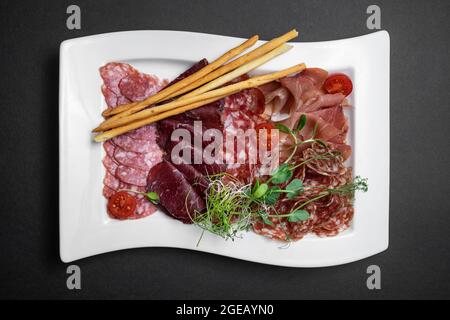 vue de dessus d'une assiette de viande froide avec salami, prosciutto, saucisse et bâtonnets de pain Banque D'Images