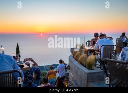 L'île de Lefkada. Grèce- 08.07.2021: Les gens et les touristes appréciant la cuisine fine dans un restaurant au sommet d'une colline avec vue incroyable sur le coucher du soleil. Banque D'Images