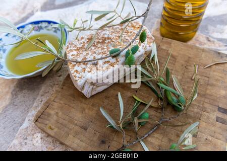 Olives vertes et branche sur une planche en bois avec un bol et une bouteille d'huile d'olive pressée à froid. Banque D'Images