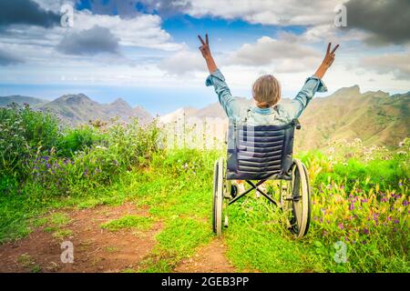 Femme handicapée en fauteuil roulant sur une colline de montagne avec vue Banque D'Images