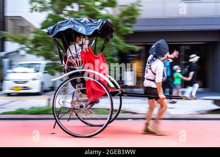 Un pousse-pousse ou un jinrikisha transporte les touristes autour du temple bouddhiste Sensoji et du quartier historique d'Asakusa à Tokyo, au Japon. Banque D'Images