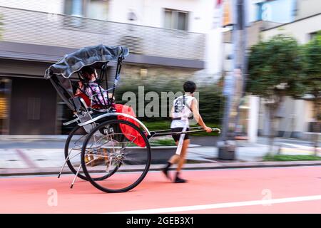 Un pousse-pousse ou un jinrikisha transporte les touristes autour du temple bouddhiste Sensoji et du quartier historique d'Asakusa à Tokyo, au Japon. Banque D'Images