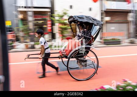 Un pousse-pousse ou un jinrikisha transporte les touristes autour du temple bouddhiste Sensoji et du quartier historique d'Asakusa à Tokyo, au Japon. Banque D'Images